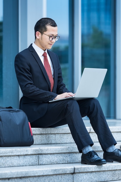 Mężczyźni biznesu korzystają z laptopów przy wejściu do budynku biurowego