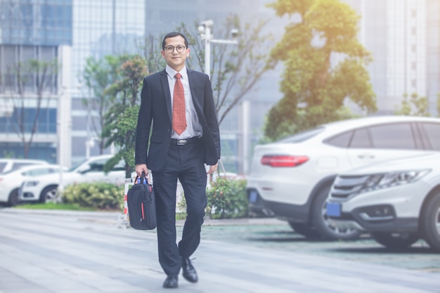 Mężczyźni biznesu przewożą laptopy na parkingu