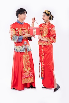 Mężczyźni i kobiety noszący cheongsam stojących z czerwonymi torbami