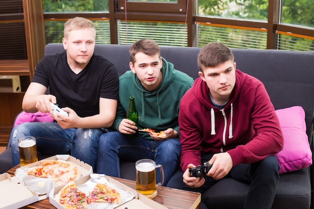 Bezpłatne zdjęcie mężczyźni kibice oglądają piłkę nożną w telewizji i piją piwo. trzech mężczyzn pije piwo i razem bawi się w barze