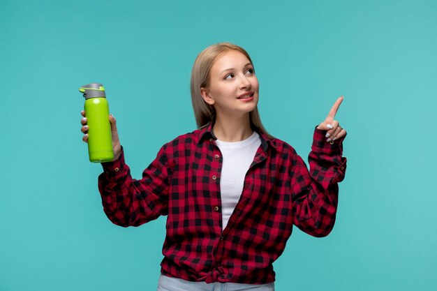 Międzynarodowy dzień studentów ładna blondynka w czerwonej koszuli w kratę, patrząc w górę i trzymając butelkę