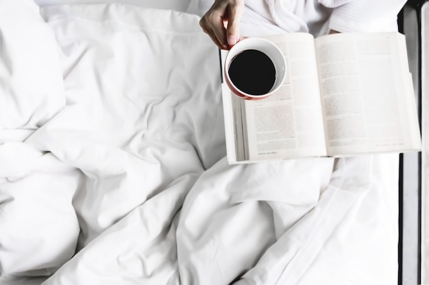 Miękkie zdjęcie kobiety na łóżku z starą książkę i filiżankę kawy i kopia przestrzeń.