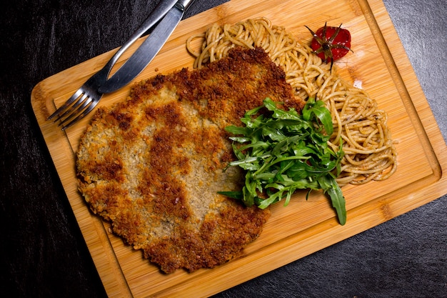 Mięsny langet na drewnianej desce z spaghetti arugula pomidorowym odgórnym widokiem