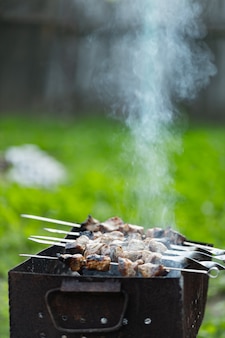 Mięso smaży się na szaszłykach na mangalu. mięso grillowane na szaszłykach w dymie. gotowanie z grilla kebab w wiejskim domu. skopiuj miejsce