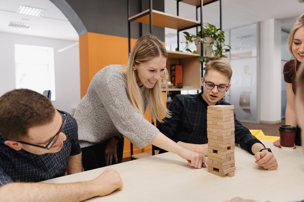 Mieszana drużyna bawić się blokuje drewnianą grę w biurze