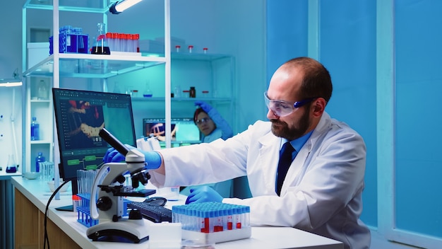 Bezpłatne zdjęcie mikrobiolog badacze biotechnologii pracujący nad opracowaniem szczepionek późno w nocy w laboratorium wyposażonym w chemię
