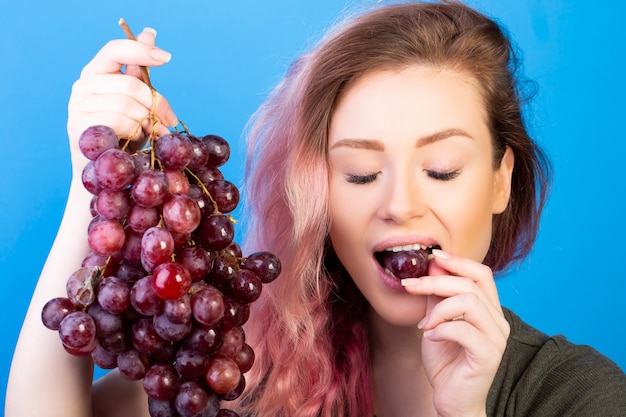 Bezpłatne zdjęcie miła kobieta je winogrona z zamkniętymi oczami