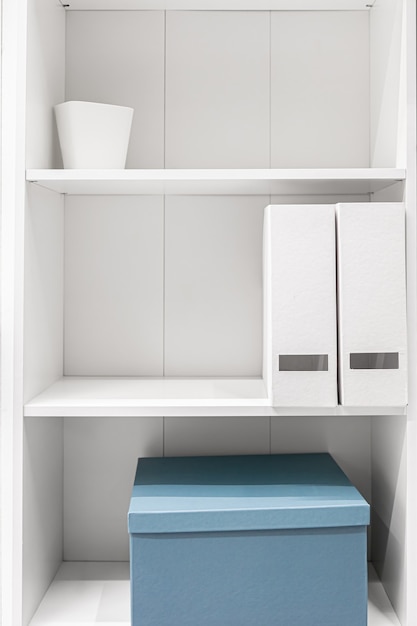 Minimalistyczna szafa, do połowy puste półki w białej szafie, biała szafa w środku.