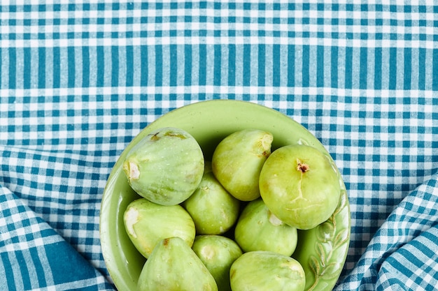 Bezpłatne zdjęcie miska soczystych zielonych fig na niebieskim obrusie.