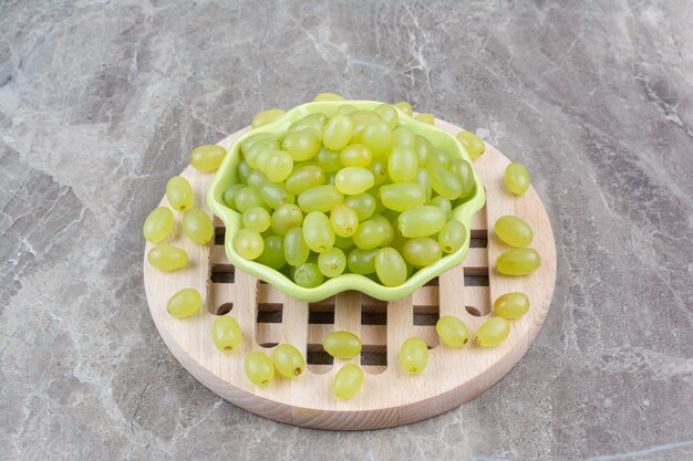 Miska z zielonych winogron na kawałku drewna.