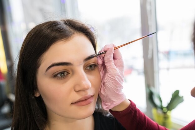 Mistrz kobieta umieściła farbę do brwi w salonie piękności podczas makijażu