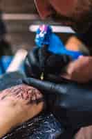 Bezpłatne zdjęcie mistrz robi tatuaż na ramieniu z igłą