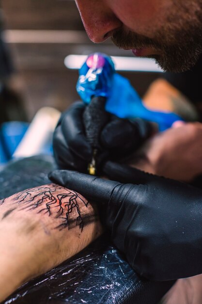 Mistrz robi tatuaż na ramieniu z igłą