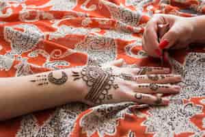 Bezpłatne zdjęcie mistrz tatuażu mehndi malować na ręce kobiety