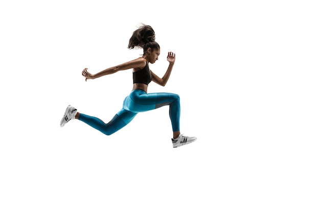 Bezpłatne zdjęcie młoda afrykańska kobieta działa na białym tle na tle białego studia. jedna biegaczka lub jogger. sylwetka sportowca joggingu