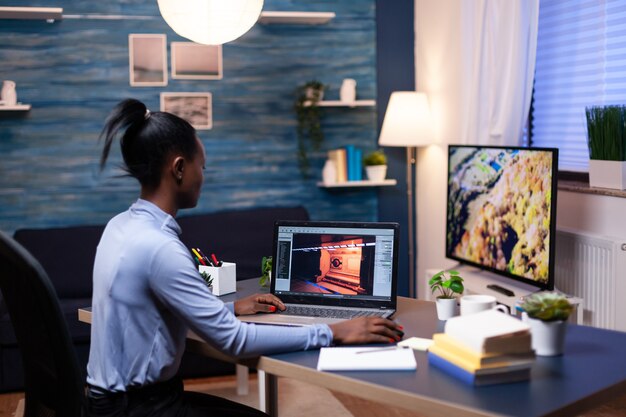 Młoda afrykańska kobieta testuje profesjonalną grę online na laptopie w domu późno w nocy. Profesjonalny gracz sprawdzający cyfrowe gry wideo na swoim komputerze z nowoczesną technologią sieci bezprzewodowej.