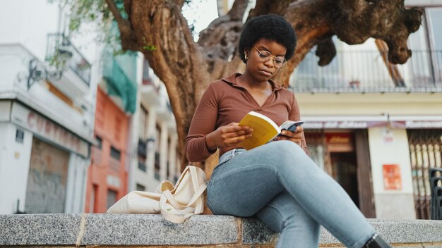Młoda Afrykańska kobieta wygląda na skoncentrowaną podczas czytania książki un