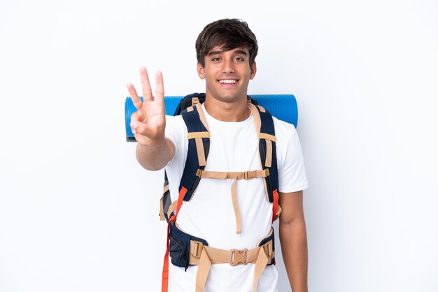 Młoda alpinistka z dużym plecakiem na odosobnionym białym tle szczęśliwa i licząca trzy palcami