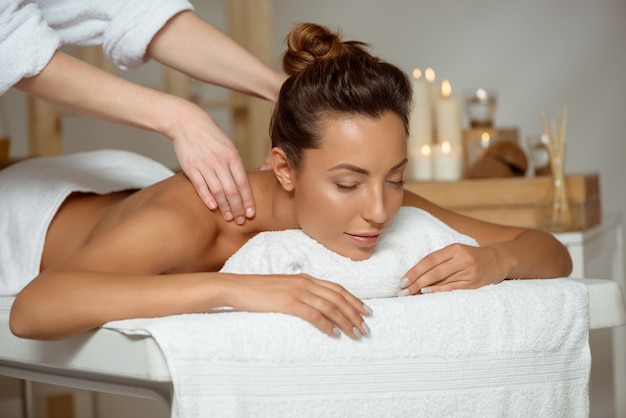 Młoda atrakcyjna kobieta ma masaż relaksuje w zdroju salonie.