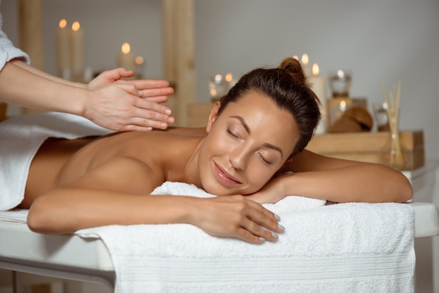 Młoda atrakcyjna kobieta ma masaż relaksuje w zdroju salonie.