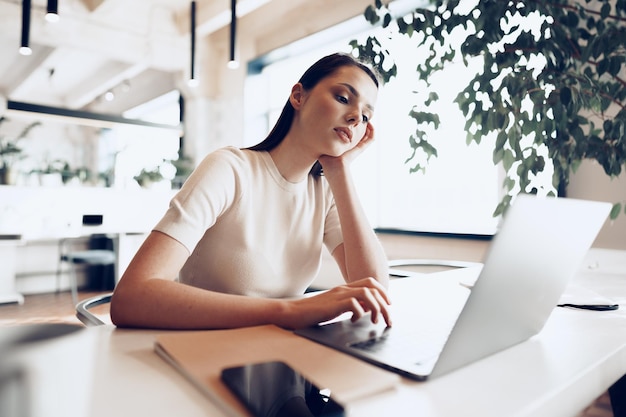 Młoda atrakcyjna kobieta pracuje na laptopie w biurze