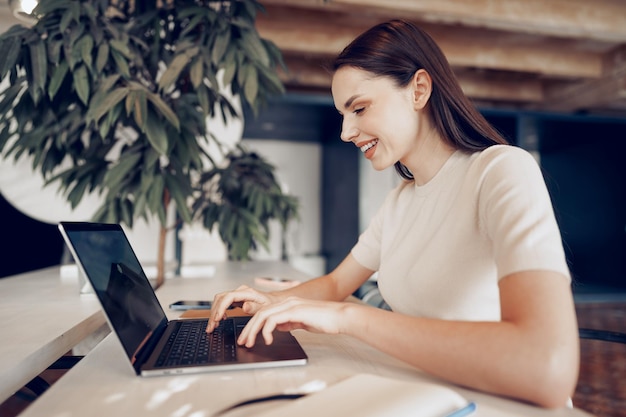 Młoda atrakcyjna kobieta pracuje na laptopie w biurze