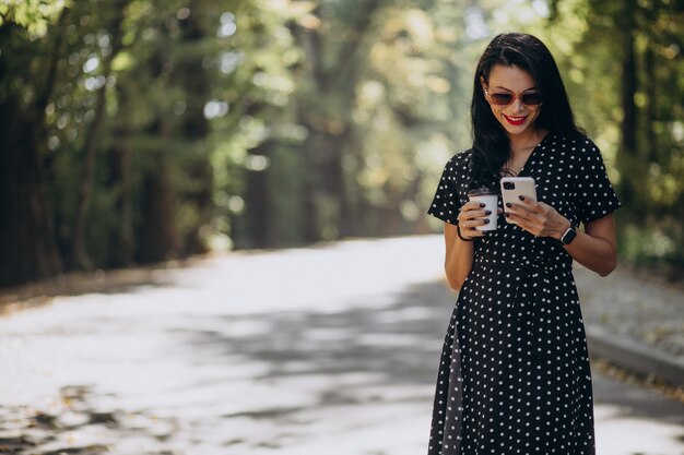 Młoda atrakcyjna kobieta rozmawia przez telefon w parku