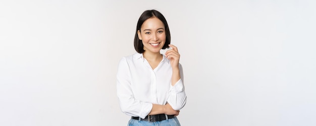 Młoda azjatycka kobieta profesjonalny przedsiębiorca stojący w odzieży biurowej uśmiechający się i wyglądający pewnie na białym tle