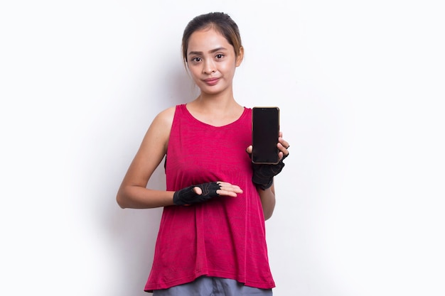 Młoda azjatycka sportowa kobieta demonstruje telefon komórkowy na białym tle