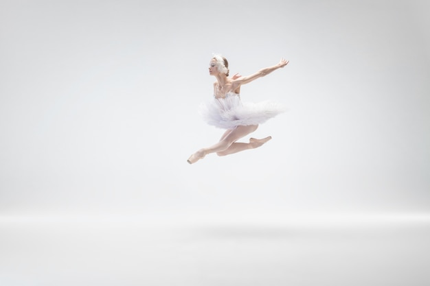Młoda baletnica wdzięku na tle białego studia