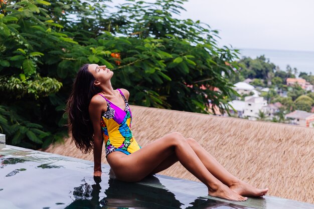 Młoda bardzo pozytywna szczęśliwa szczupła kobieta w kolorowym stroju kąpielowym w luksusowej niesamowitej willi hotelowej, ciesząc się pięknym dniem na wakacjach w Tajlandii