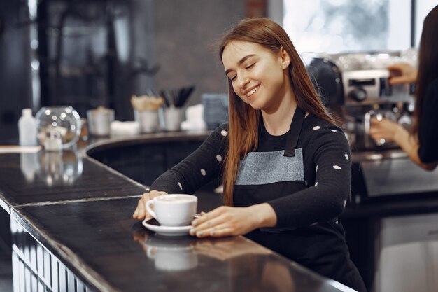 Młoda barista dziewczyna robi kawę i uśmiecha się