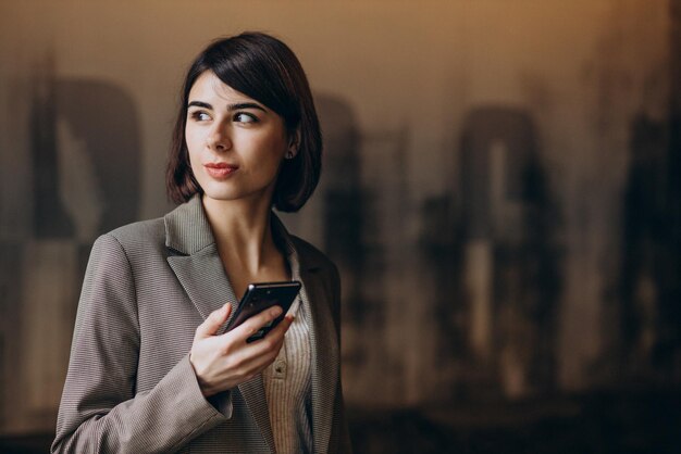 Młoda biznesowa kobieta korzysta z telefonu w kawiarni