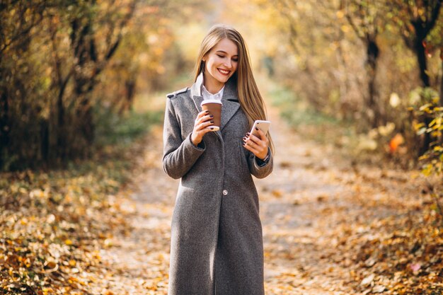 Młoda biznesowa kobieta opowiada na telefonie i pije kawę
