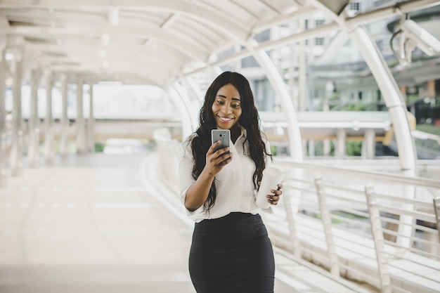 Młoda biznesowa kobieta patrzeje na jej telefonie komórkowym podczas pracować pracować.
