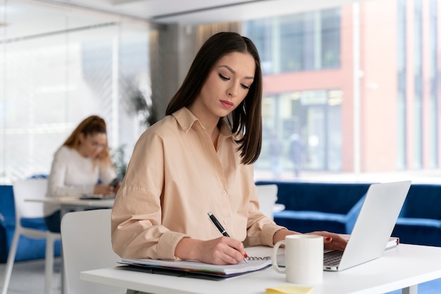 Młoda biznesowa kobieta pracuje przy biurku z laptopem