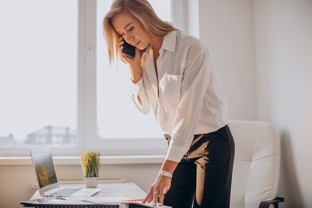 Młoda biznesowa kobieta używa telefonu w biurze