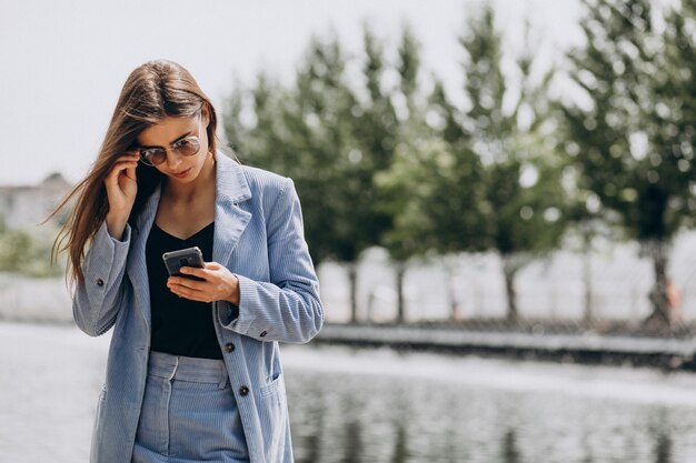 Młoda biznesowa kobieta używa telefonu w parku