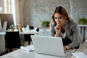 Bezpłatne zdjęcie młoda bizneswoman surfuje po sieci na komputerze podczas pracy w biurze