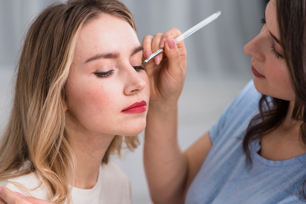 Młoda blond kobieta i artysta robi oka makeup