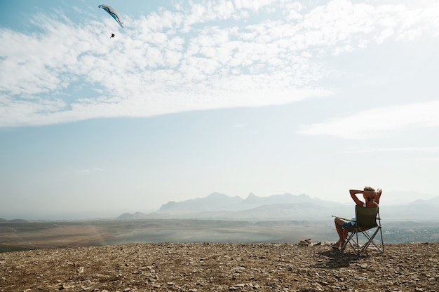 Młoda blond kobieta siedzi na szczycie wzgórza