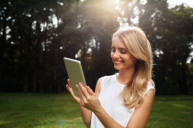 Młoda blond kobieta trzymając tabletkę