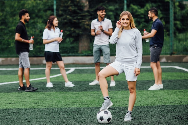 Młoda blond kobieta uśmiechnięta i szczęśliwa, z piłką nożną, podekscytowana grą