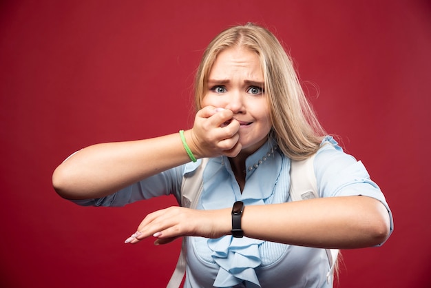 Młoda blond studentka wraca do szkoły, sprawdza godzinę i stresuje się spóźnieniem.