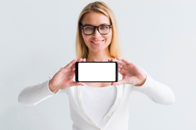 Młoda blondynka pokazuje smartphone ekran