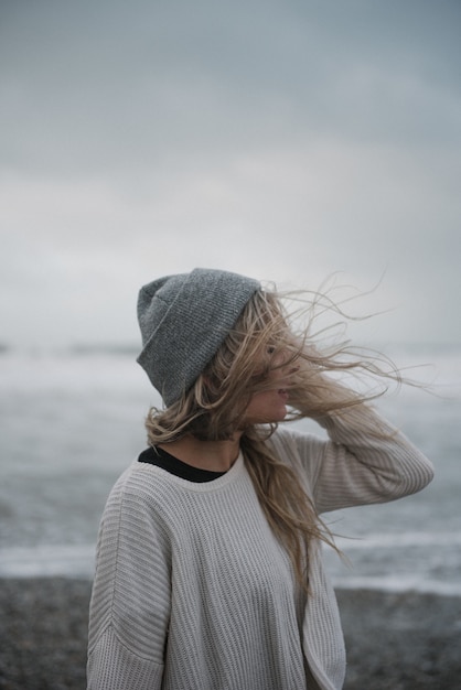 Młoda blondynka w depresji w kapeluszu spaceru po plaży w wietrzną pogodę