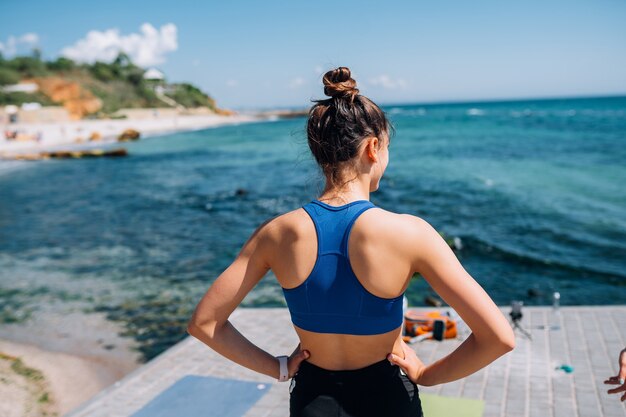 Młoda brunetka kobieta ubrana w strój fitness, rozciągający się na molo