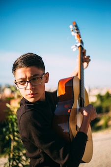 Młoda chłopiec bawić się gitarę w mieście madryt, hiszpania w tle.