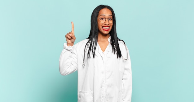 Młoda czarna kobieta czując się jak szczęśliwy i podekscytowany geniusz po zrealizowaniu pomysłu, radośnie podnosząc palec, eureka!. koncepcja lekarza