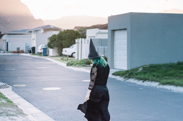 Bezpłatne zdjęcie młoda czarownica na podmiejskiej ulicy